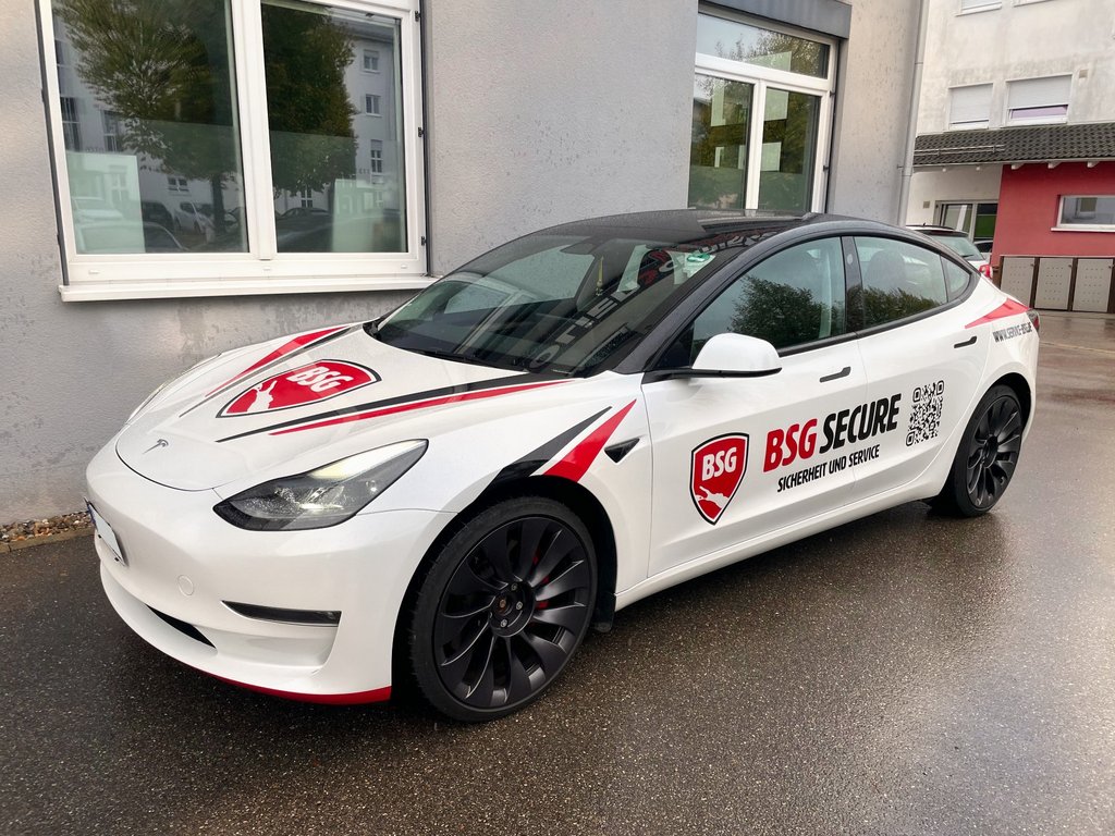 Weißer Tesla Model 3 mit rot-schwarzer Fahrzeugbeschriftung für BSG Secure