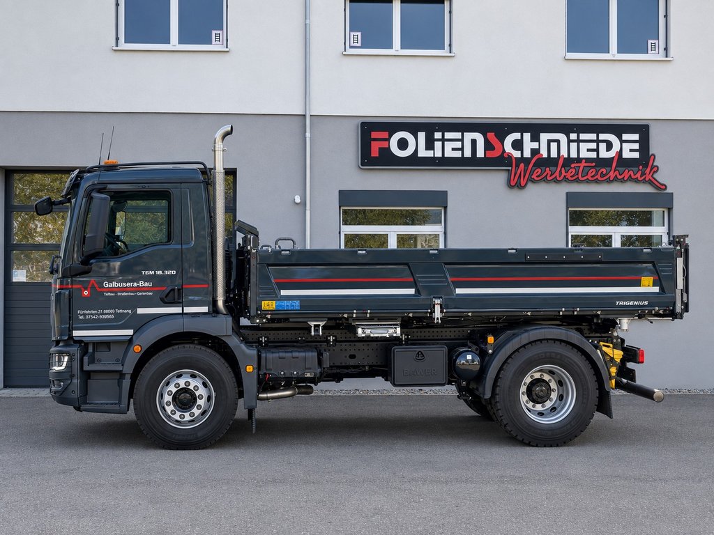 Dunkelgrauer MAN-Lkw mit rot-weißer Fahrzeugbeschriftung für Galbusera-Bau vor der Folienschmiede
