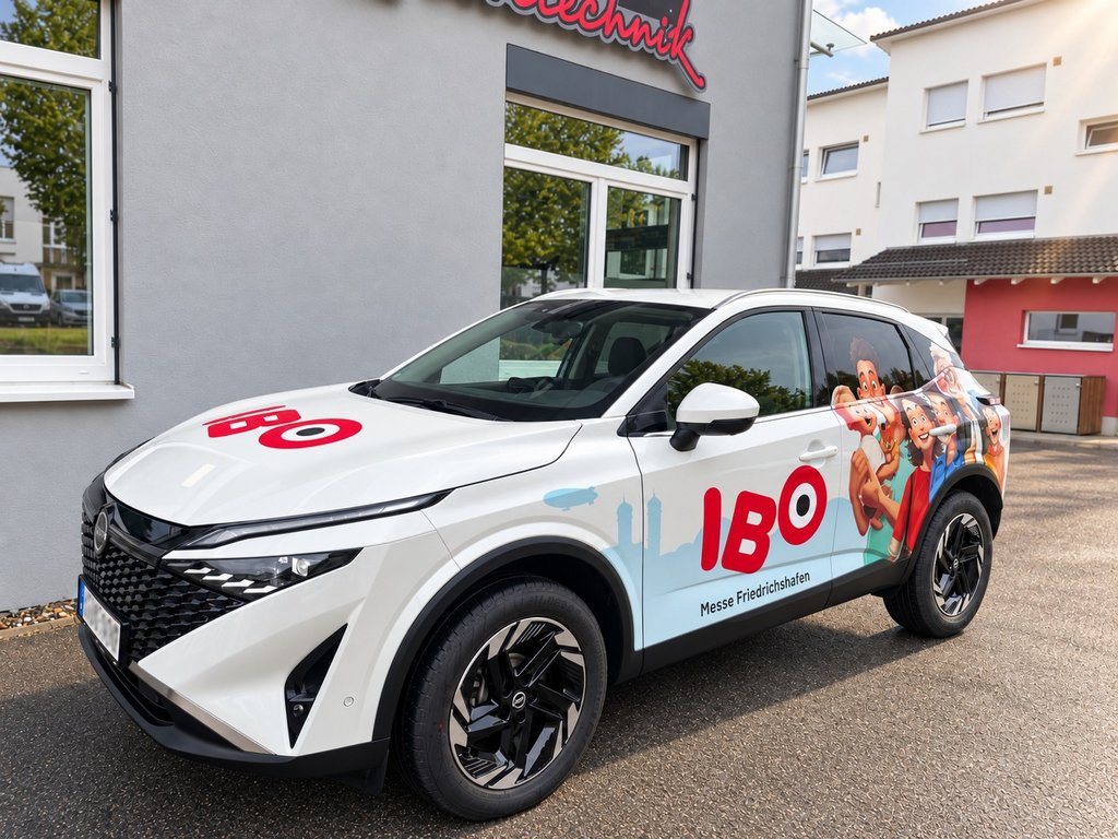 Weißer Nissan Qashqai mit IBO-Fahrzeugbeschriftung für die Messe Friedrichshafen vor der Folienschmiede