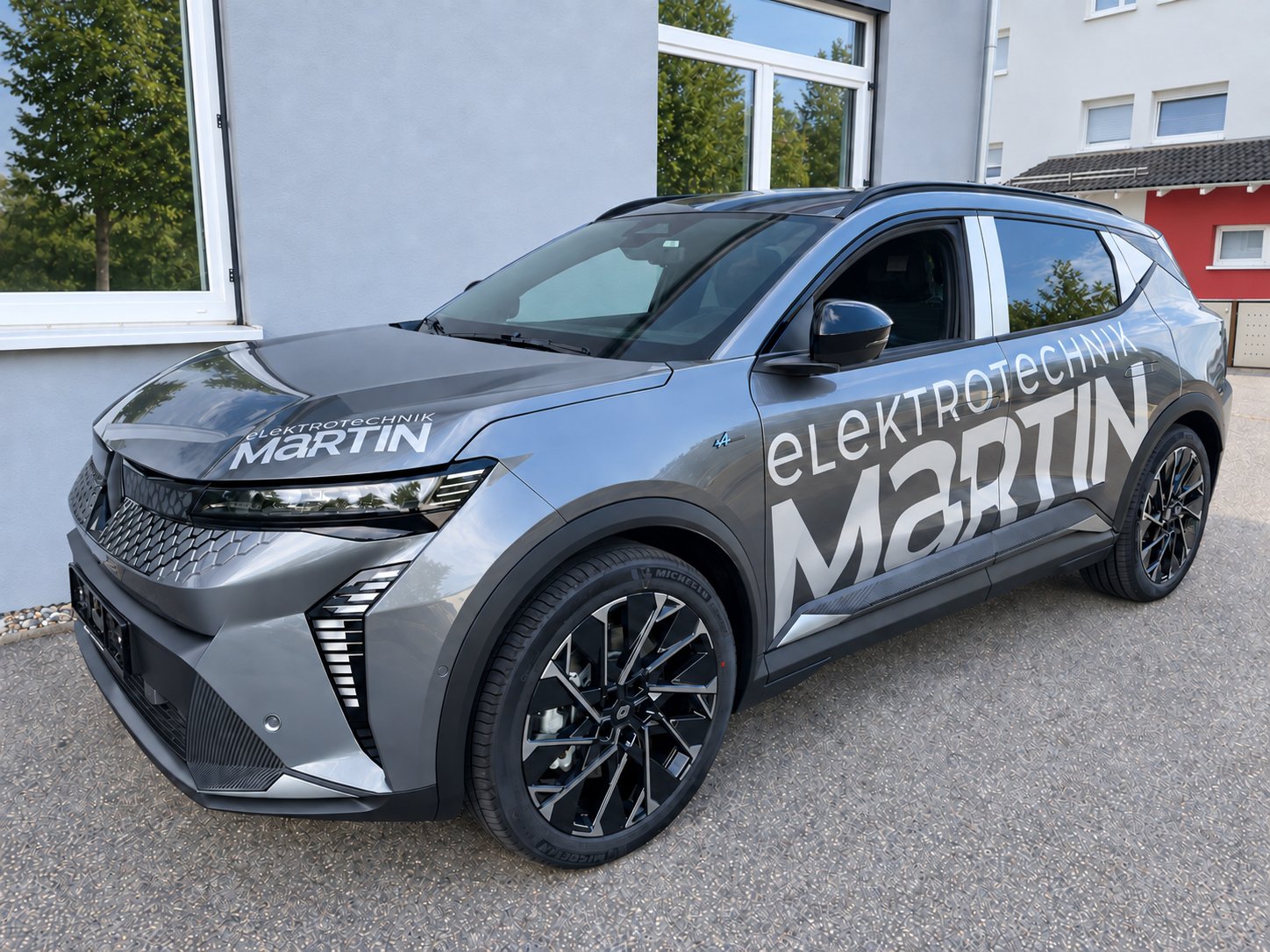 Silbergrauer Renault Scenic mit großflächiger weißer Fahrzeugbeschriftung für Elektrotechnik Martin